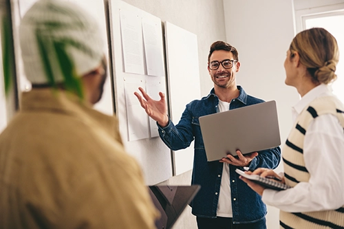 A group of people standing in front of a whiteboard, using Carrot Connect's approach to developing an innovation strategy.