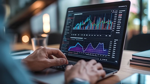 A man is using a laptop with graphs on it. This abstract image depicts different types of innovation strategies.