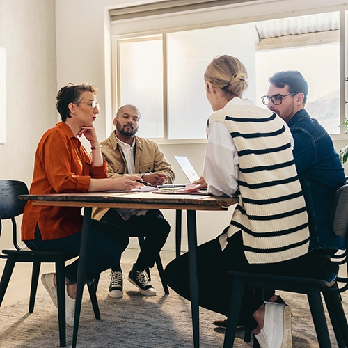 A group of people sitting around a table in an office providing oversight of a transformation implementation.